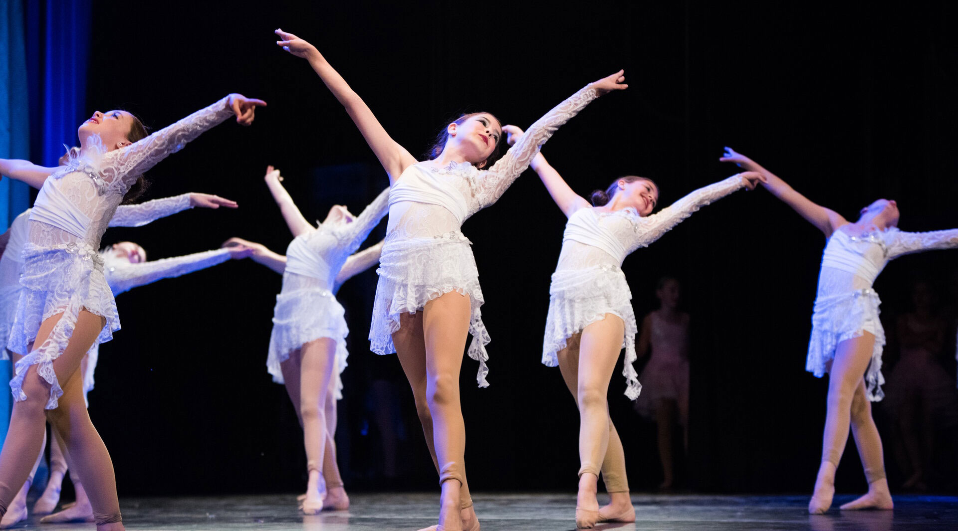 Ballet dancers performing on stage in white costumes.