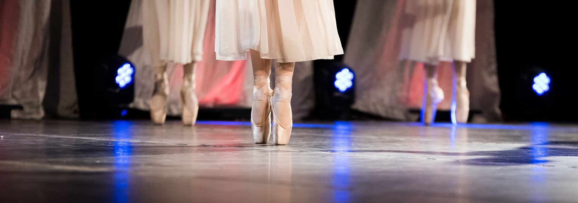 Ballet dancers standing en pointe on stage.
